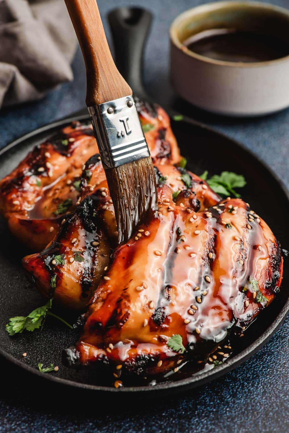 Asian glaze being brushed on grilled chicken.