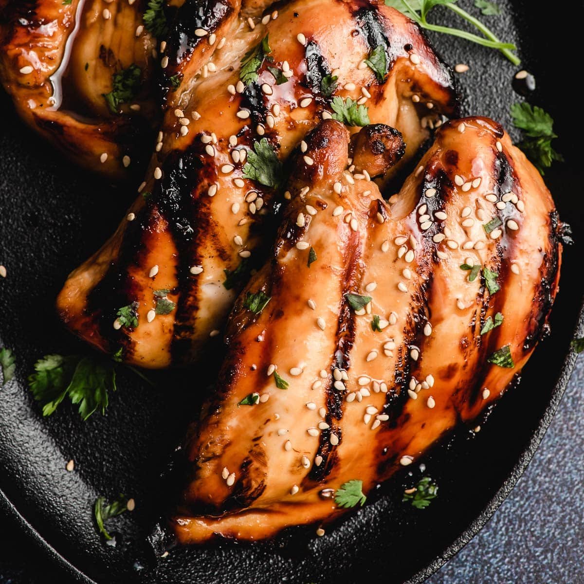 Just grilled Asian chicken on a black platter.