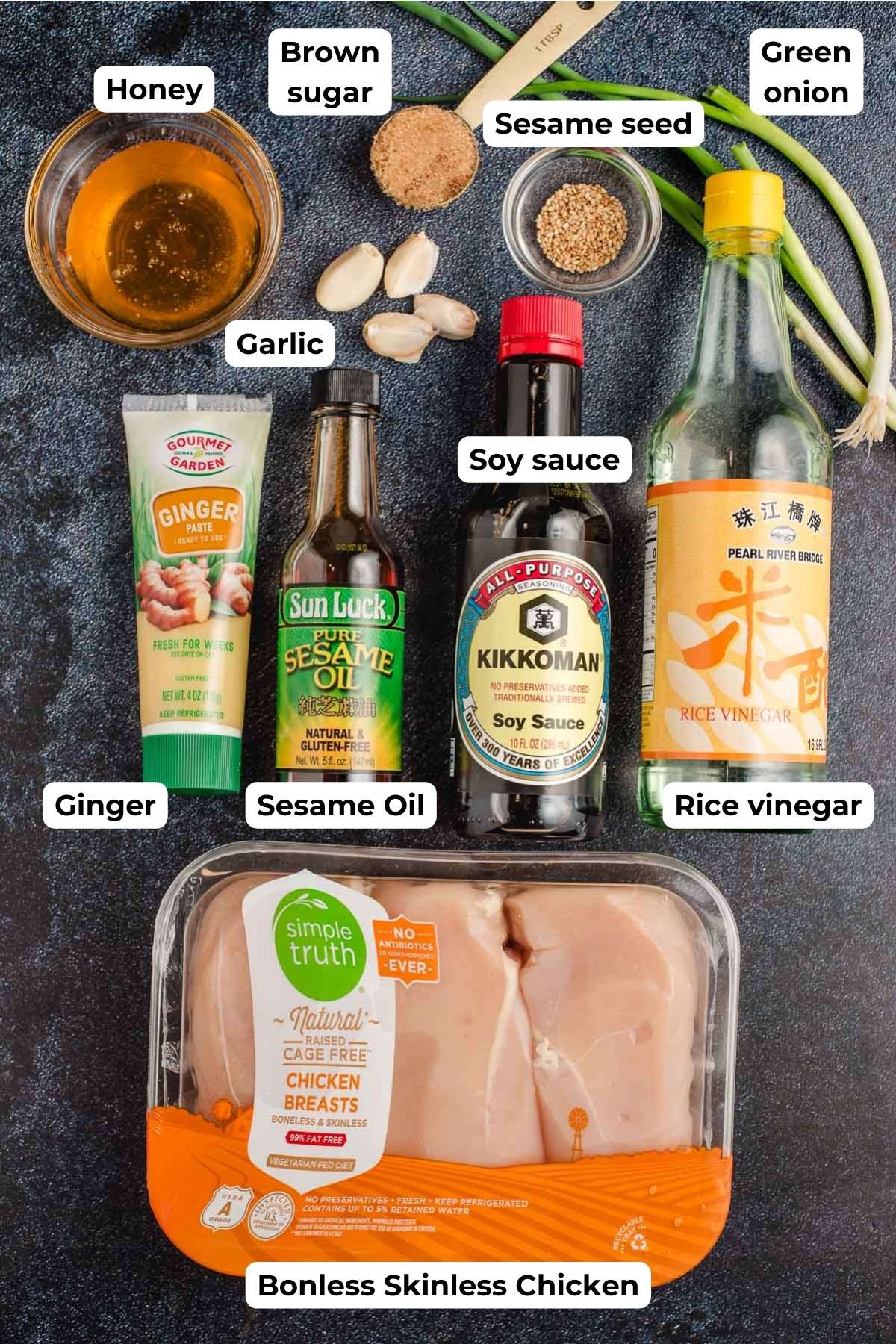Prep bowls with honey, garlic cloves, brown sugar, sesame seeds, and green onions. Bottles of ginger paste, sesame oil, soy sauce, and rice vinegar. Package of chicken breasts.