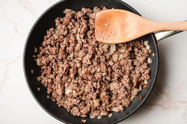 Sauteed ground beef and onions in a frying pan.
