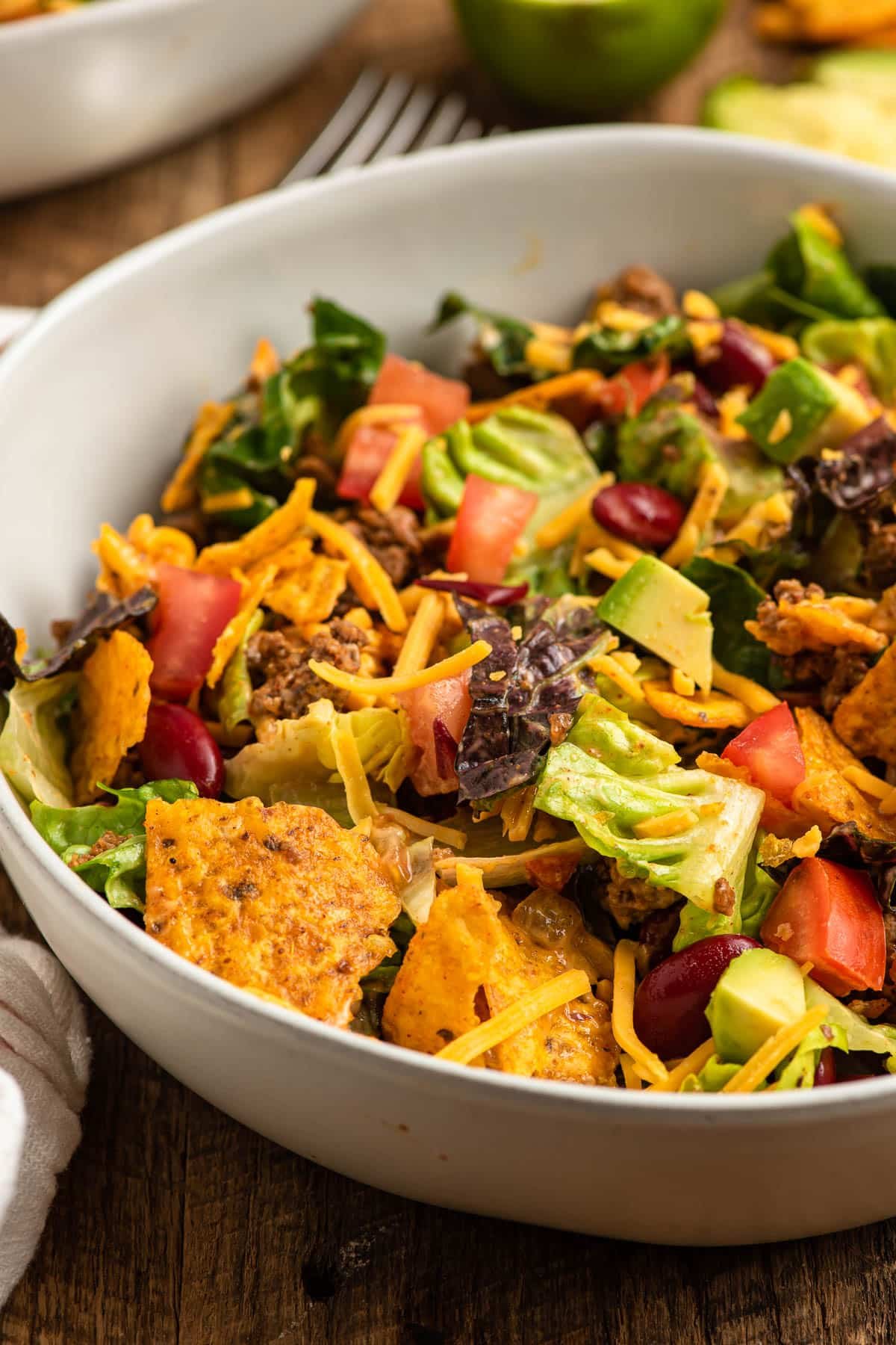 Salad with ground beef, beans, tomatoes, cheese, and Doritos in a bowl.