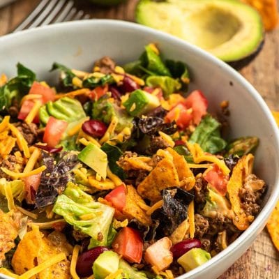 a bowl of my doritos taco salad recipe with ingredietns in the background