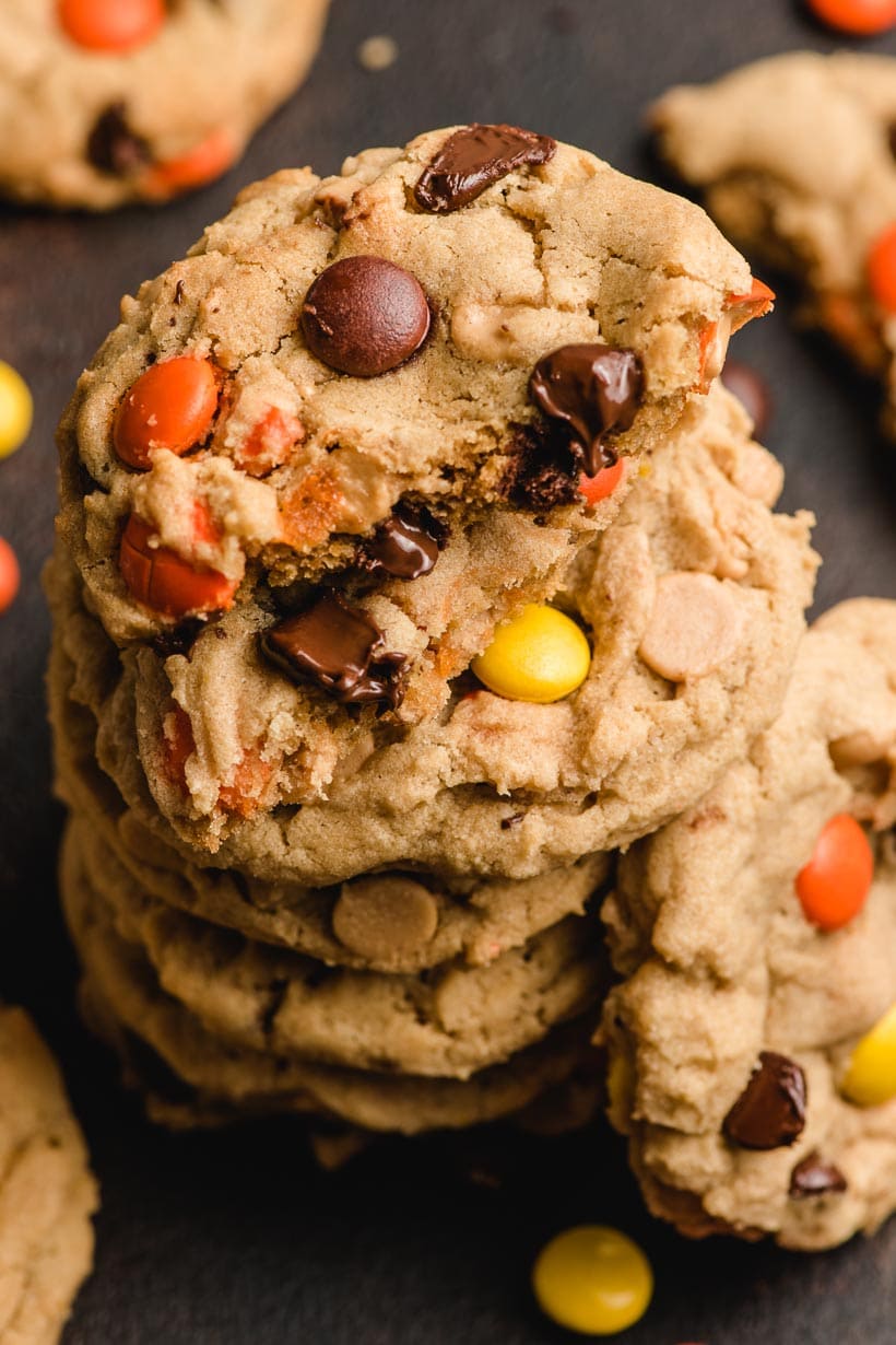 half a cookie on a stack of peanut butter cookies with reeses pieces