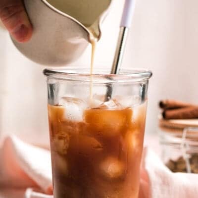 milk poured into a glass of iced chai concentrate