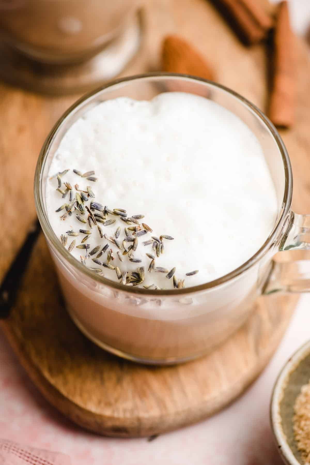 Glass mug of Earl Grey Tea topped with lavender foam and lavender buds.