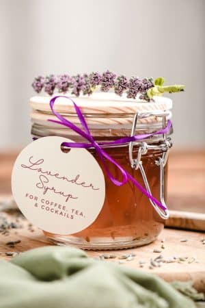 Lavender syrup in a glass jar with a homemade tag tied on with a ribbon.