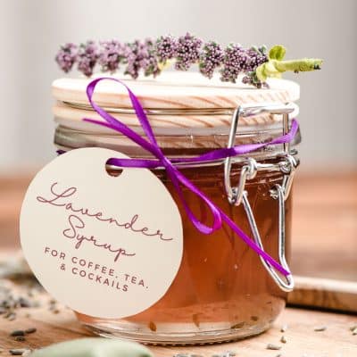 Lavender syrup in a glass jar with a homemade tag tied on with a ribbon.