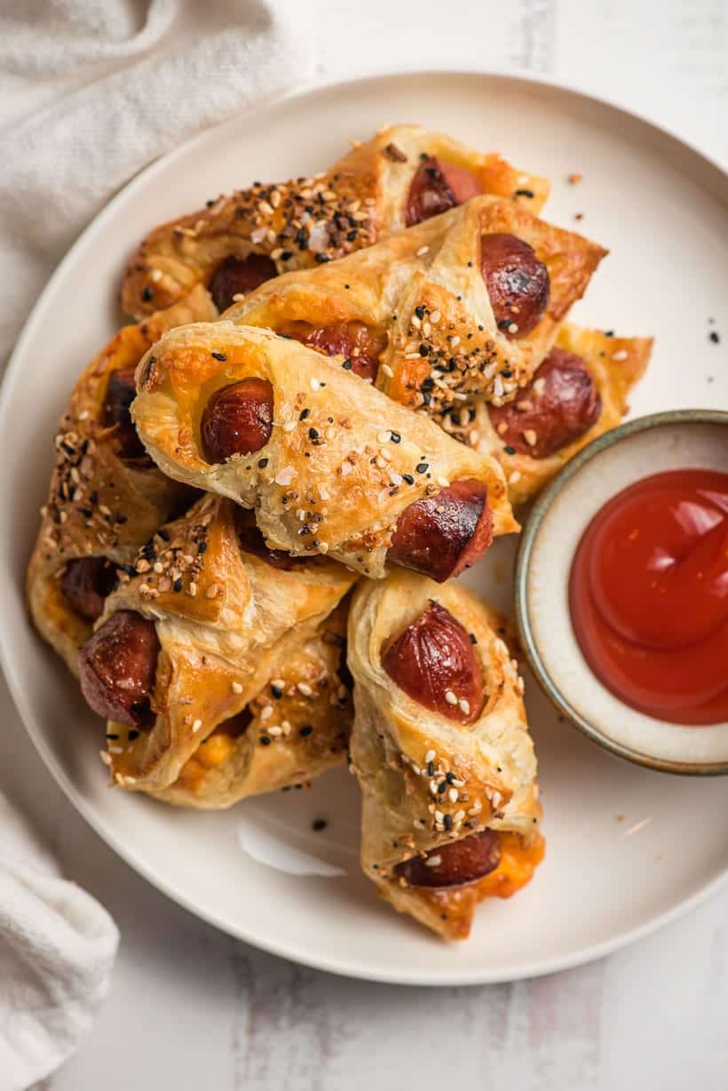 puff pastry pigs in a blanket with bowl of ketchup on a plate