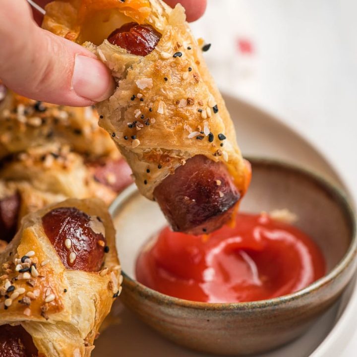 puff pastry wrapped hot dog being dipped in ketchup
