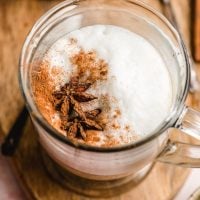 chai latte in a glass mug with star anise and cinnamon on top