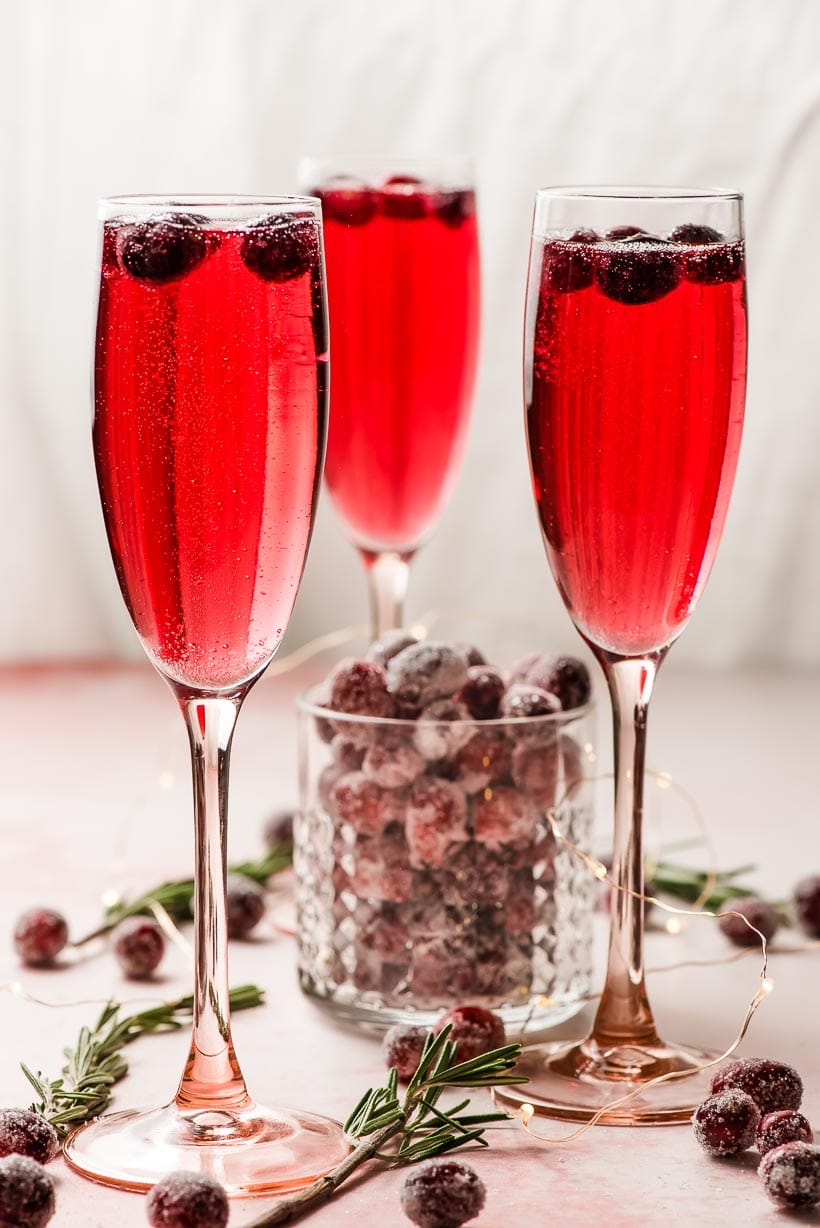 three tall pink glasses of bubbly cranberry mimosas