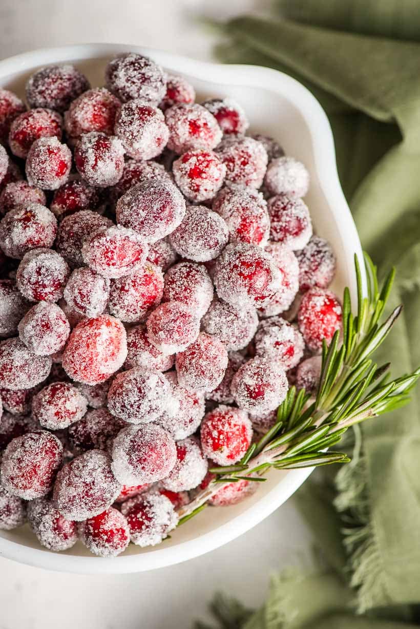 Candied Cranberries piled in a bowl with rosemary sprig