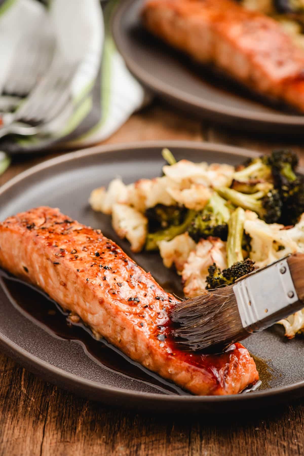 Pastry brush brushing honey soy glaze over salmon.
