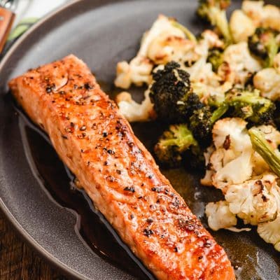 Honey Soy Salmon Filet on a gray plate with broccoli and cauliflower.