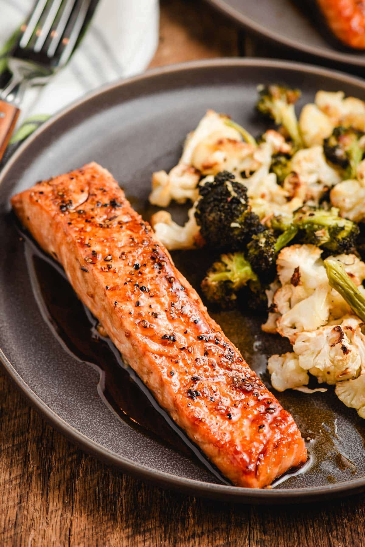 Honey Soy Salmon Filet on a gray plate with broccoli and cauliflower.