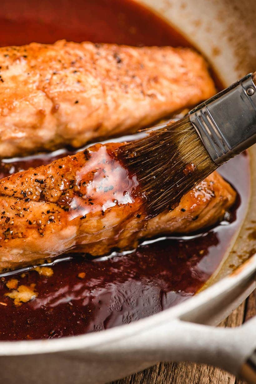 brush brushing honey soy glaze on salmon fillet