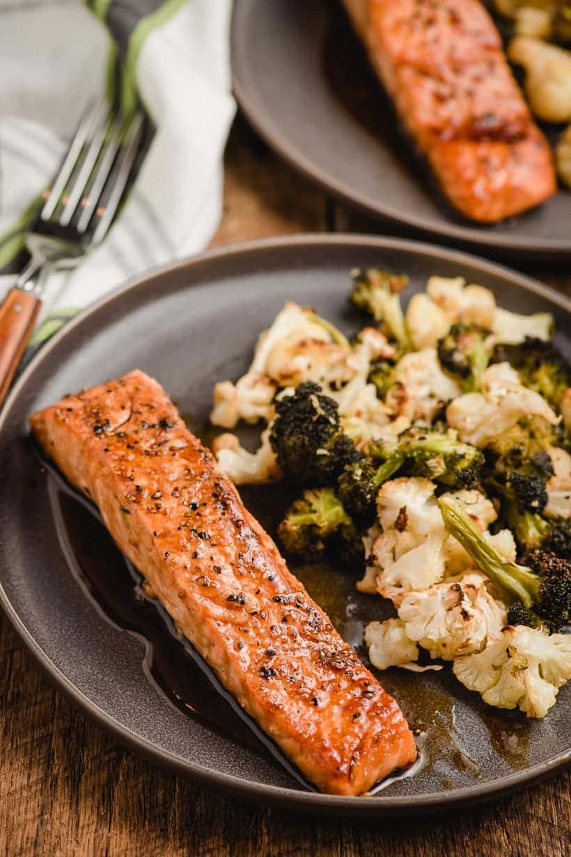 pan seared salmon on a plate with roasted broccoli and cauliflower