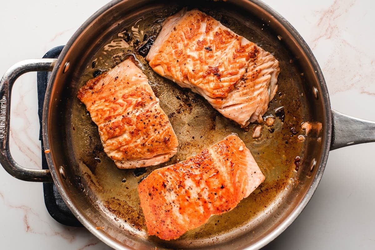Salmon filets seared in a skillet.