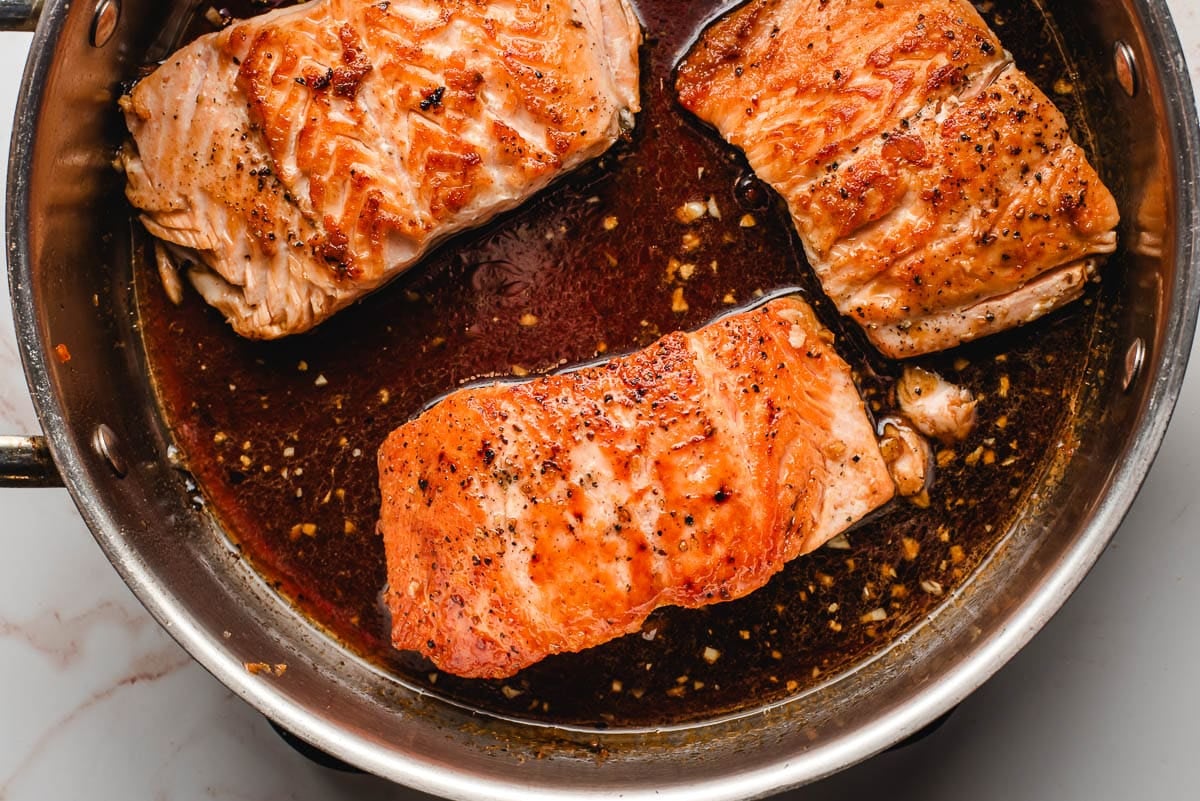 Salmon filets with honey soy glaze in a skillet.