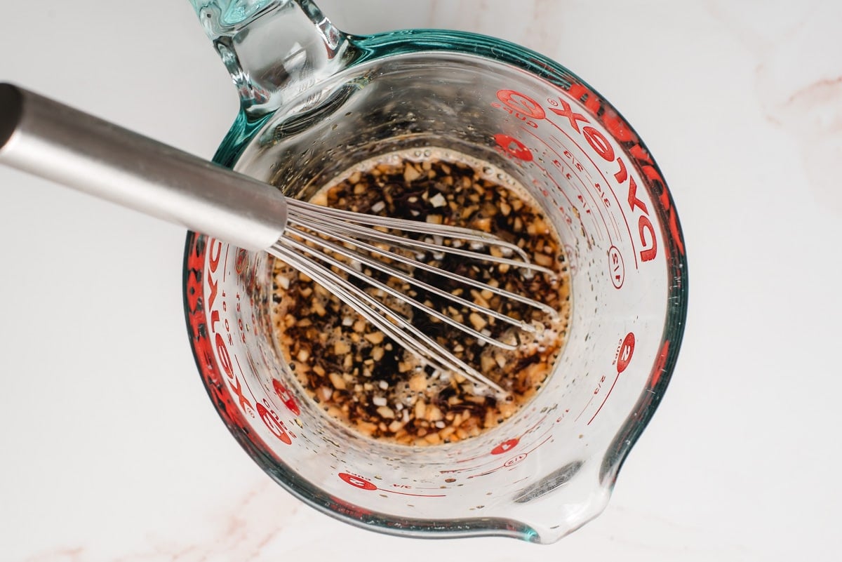 Honey soy glaze in a measuring cup with a whisk.