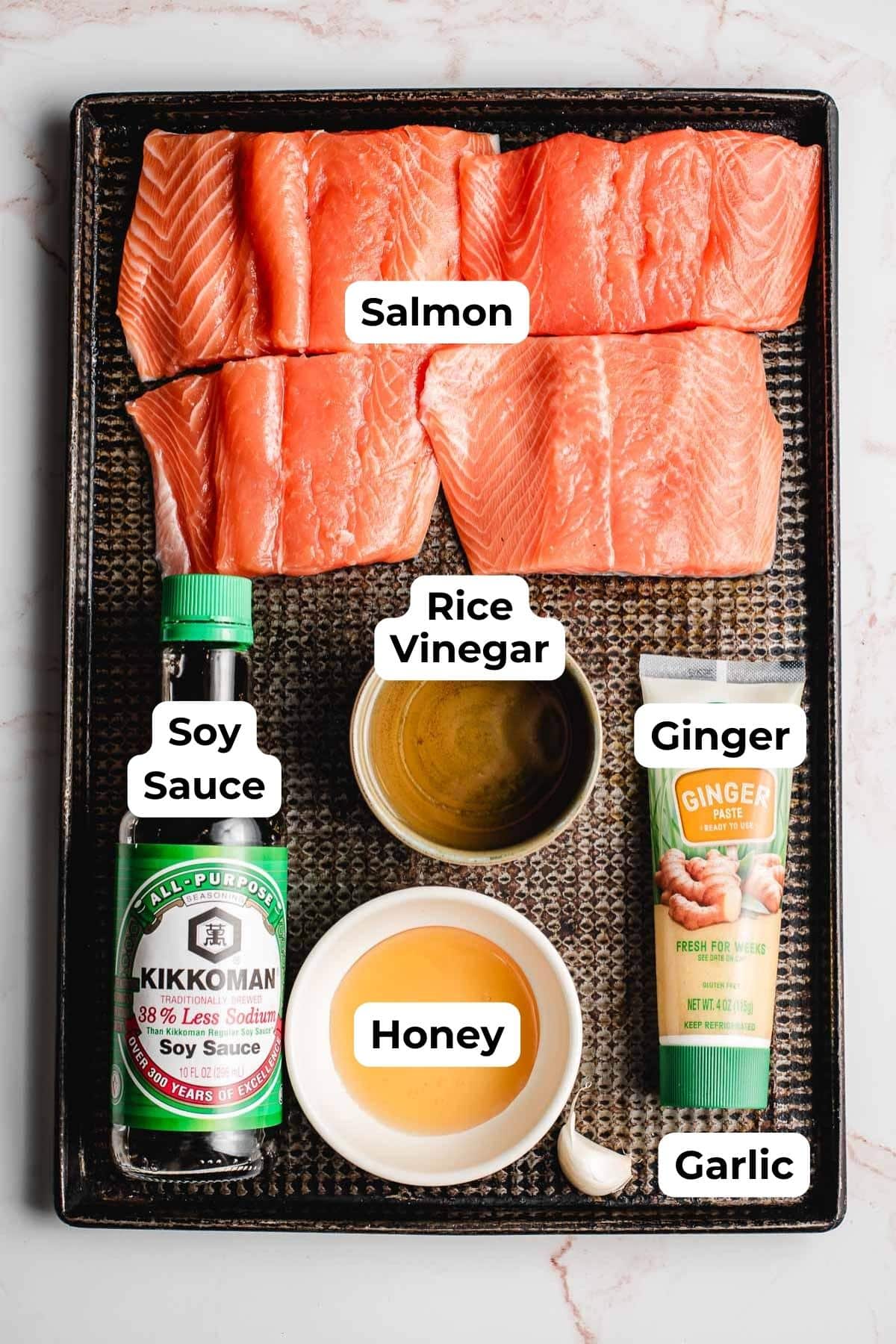 Salmon filets, soy sauce, honey, rice vinegar, garlic, and ginger on a sheet pan.