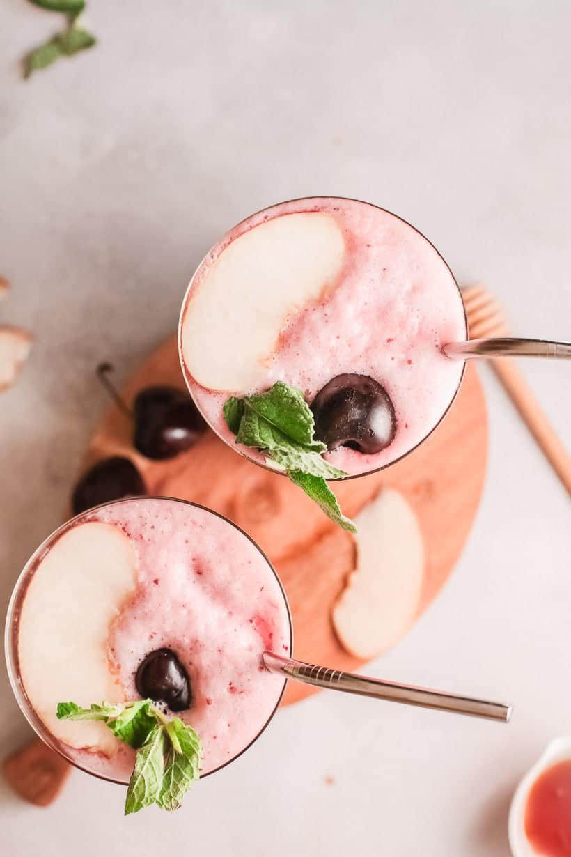 two glasses with frothy wine slushy and cherry and mint garnish