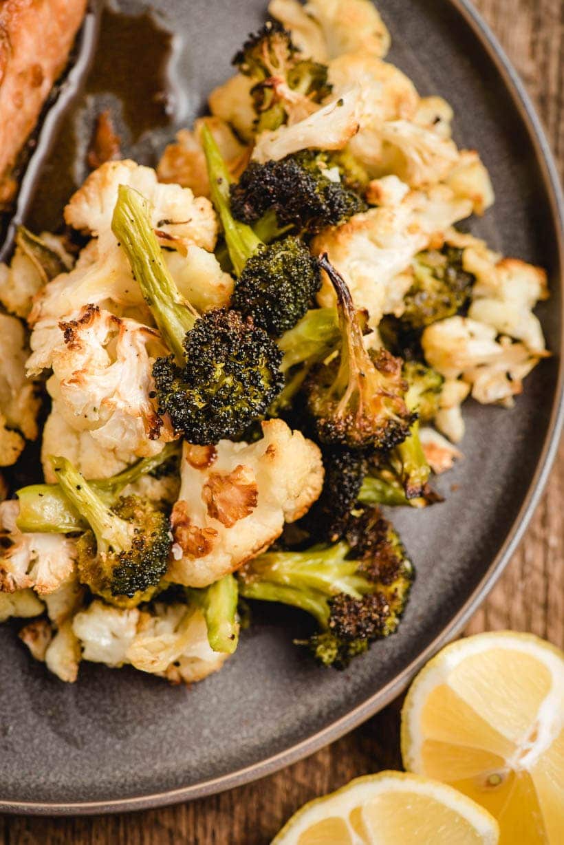 roasted broccoli and cauliflower with lemon slices on a gray plate