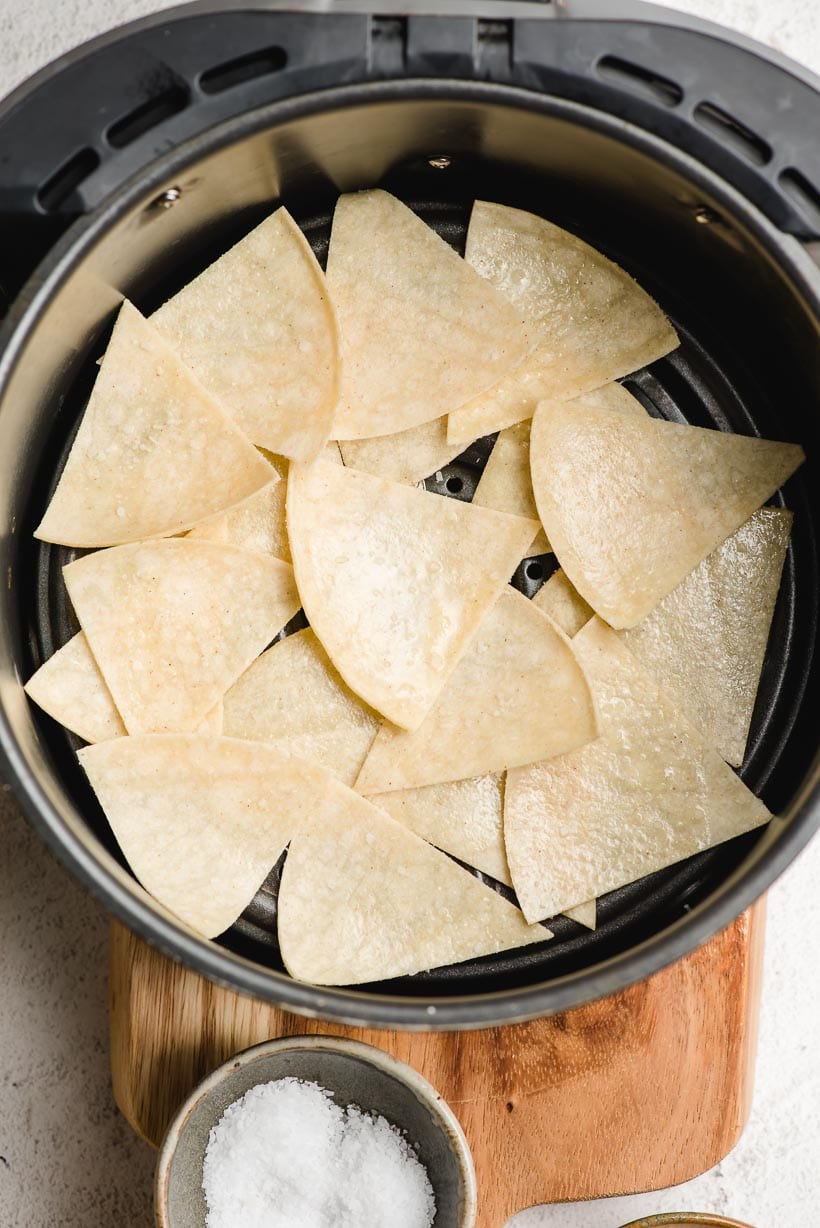 Corn tortillas cut into triangles in an air fryer basket.