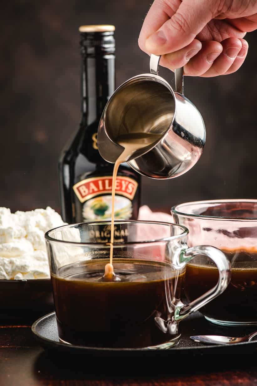 Small metal pitcher pouring Bailey's Irish cream into a cup of coffee.