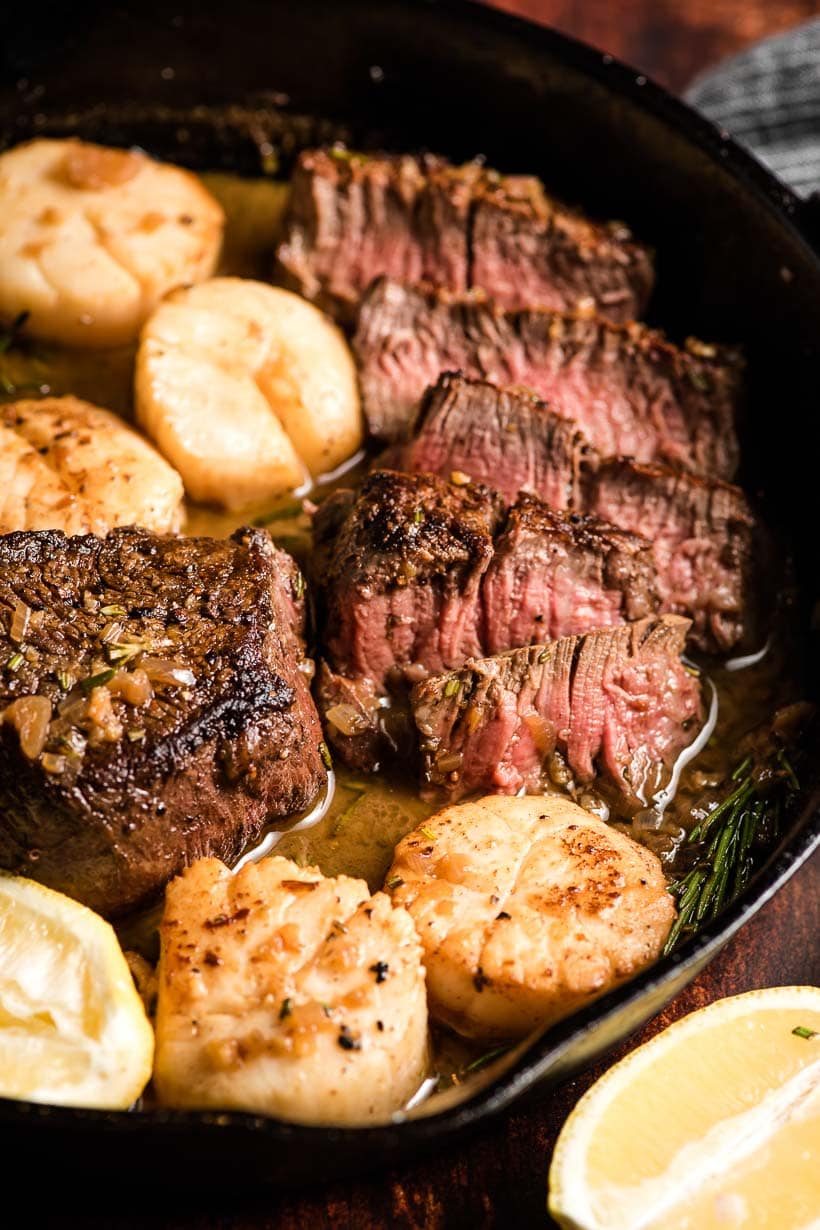 Closeup of filet and scallops in a skillet with white win sauce.