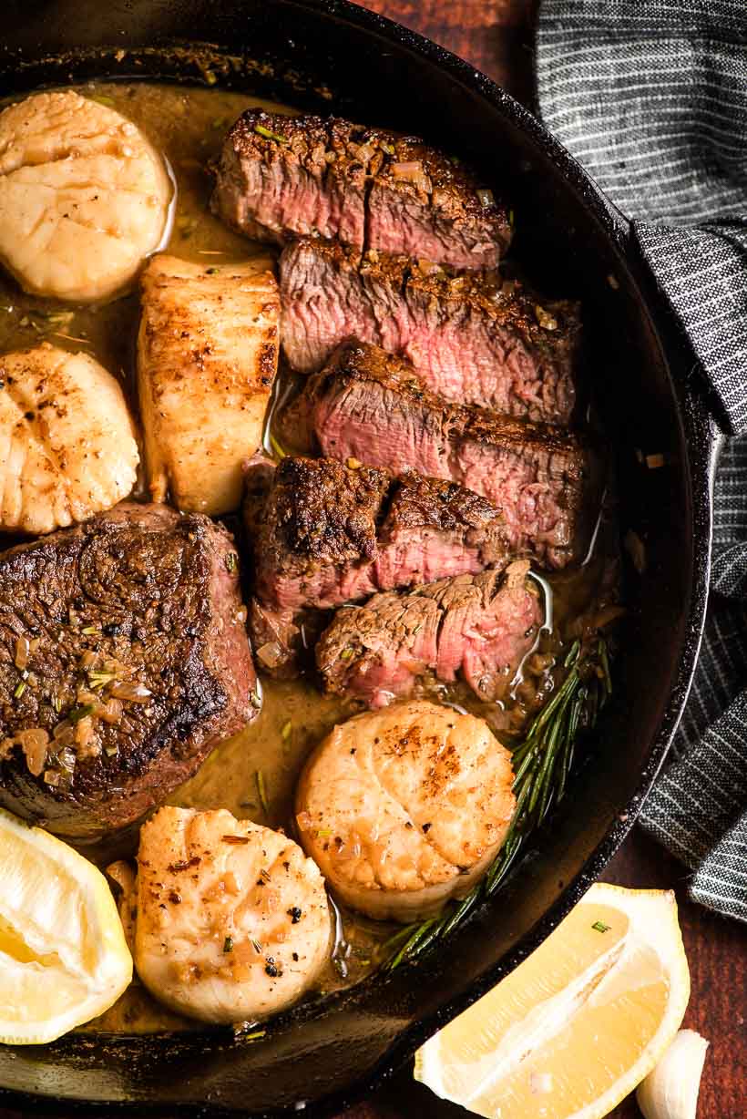 Sliced filet mignon in a cast iron skillet with scallops.