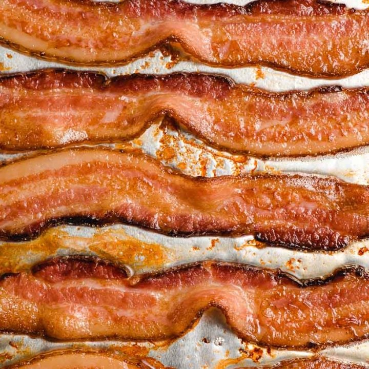 Slices of crispy oven baked bacon on a baking sheet.