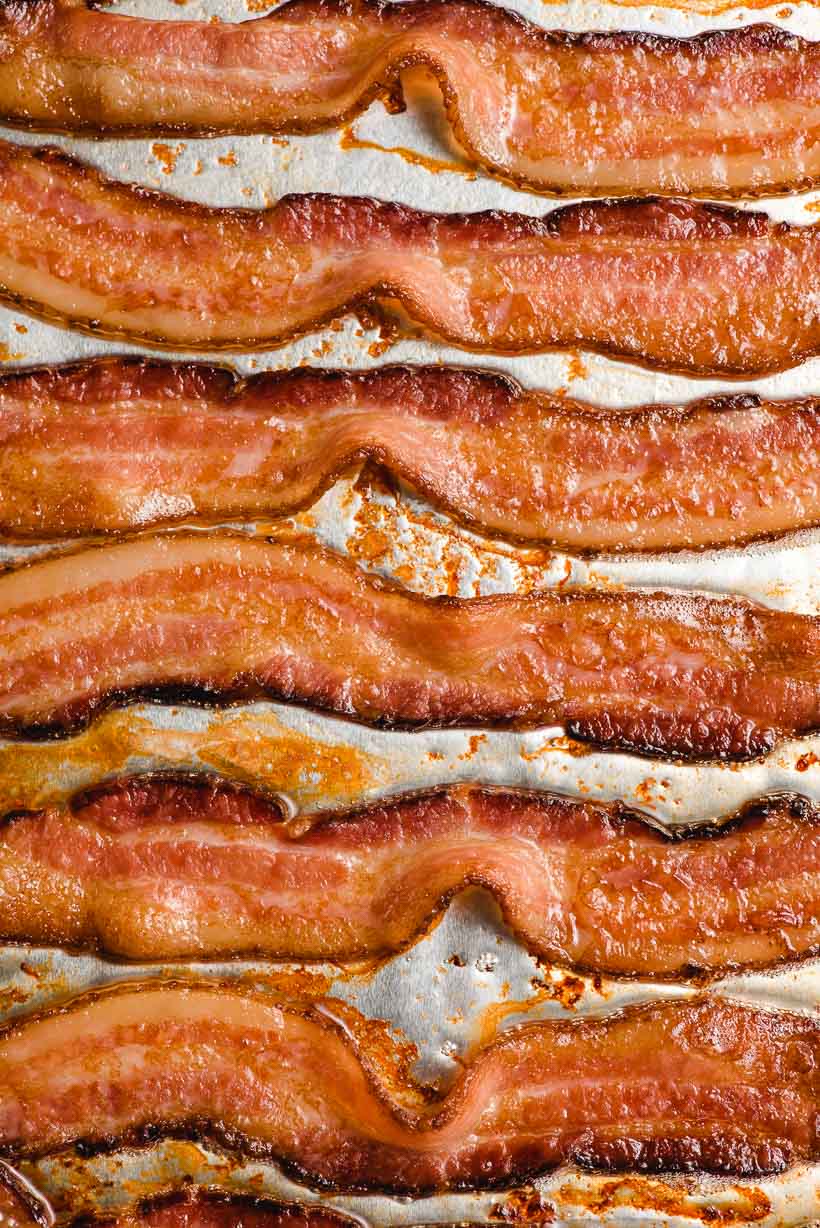 Slices of crispy oven baked bacon on a baking sheet.