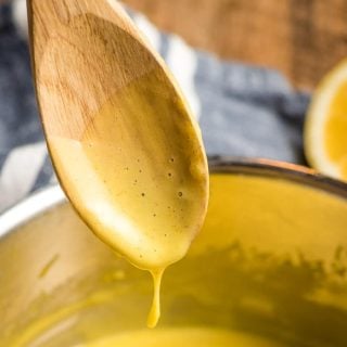 Wooden spoon dripping hollandaise sauce into a pot.