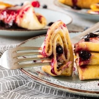 Fork taking a bite of blueberry crepes.