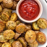 White plate filled with air fryer potatoes and a small bowl of ketchup.