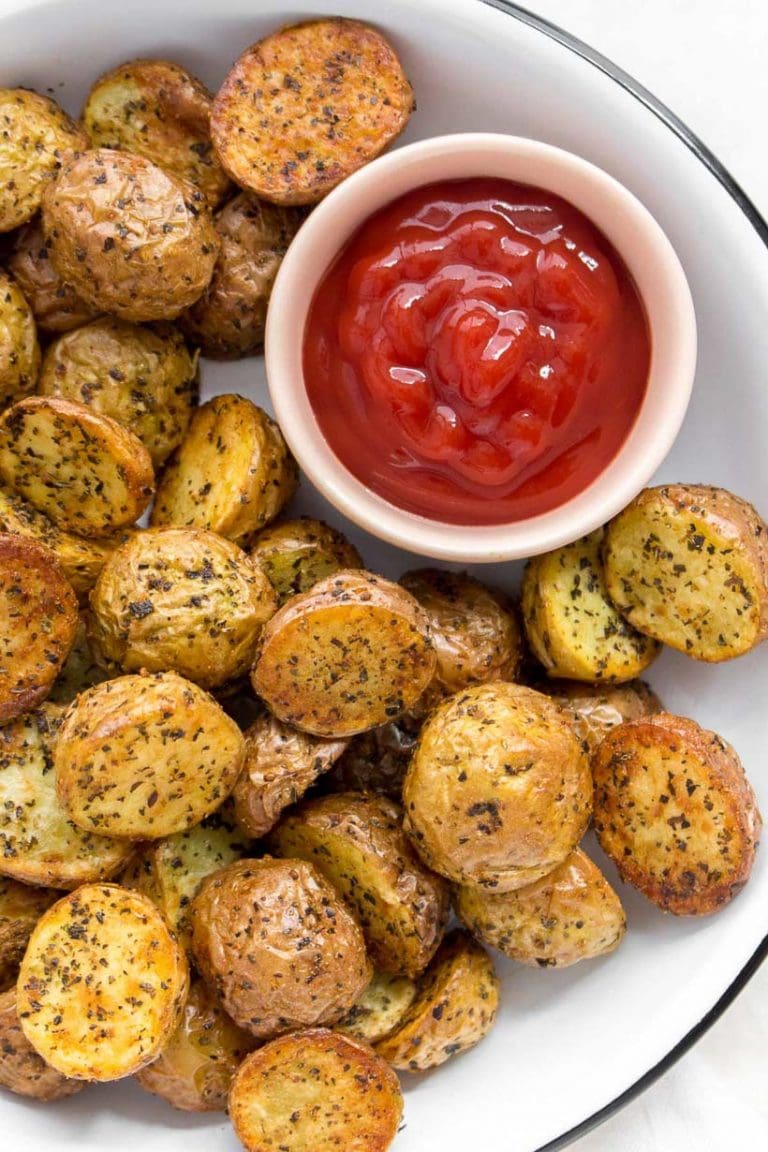 White plate filled with air fryer potatoes and a small bowl of ketchup.