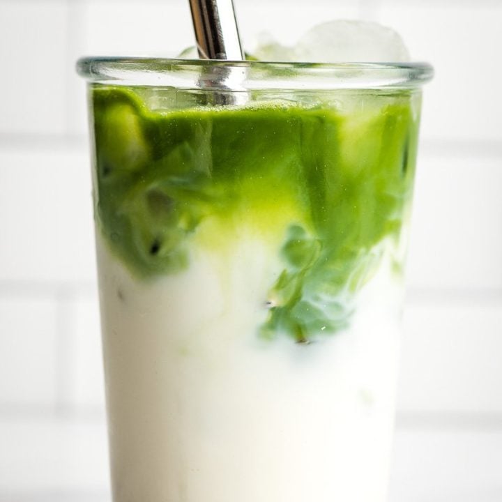 Layered Iced Matcha Latte in a large glass with a stainless steel straw.