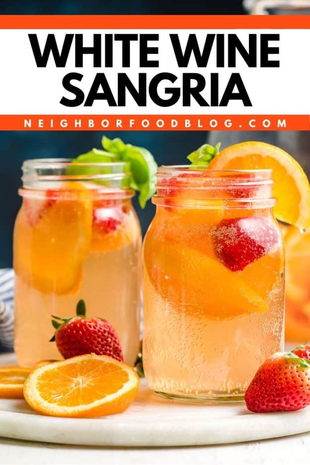 Two glass mason jars of white wine sangria with strawberries and peaches.