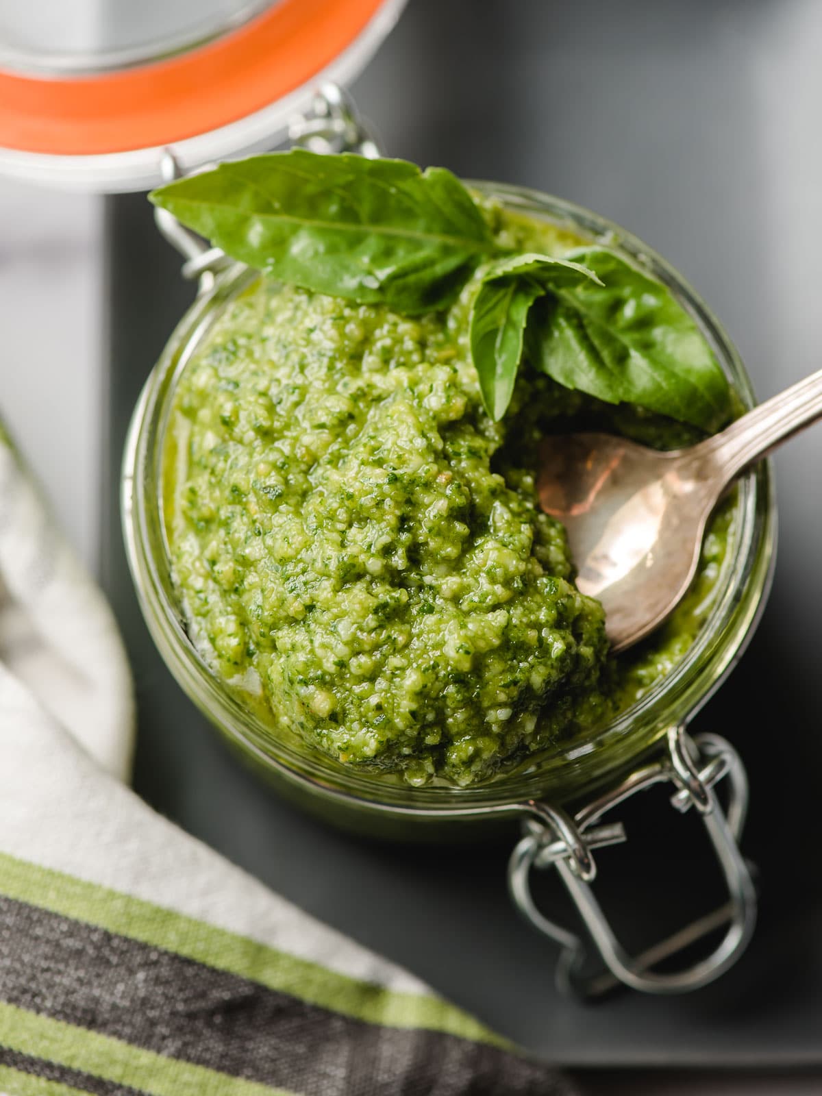 Jar of pesto with an antiqued spoon removing a spoonful.