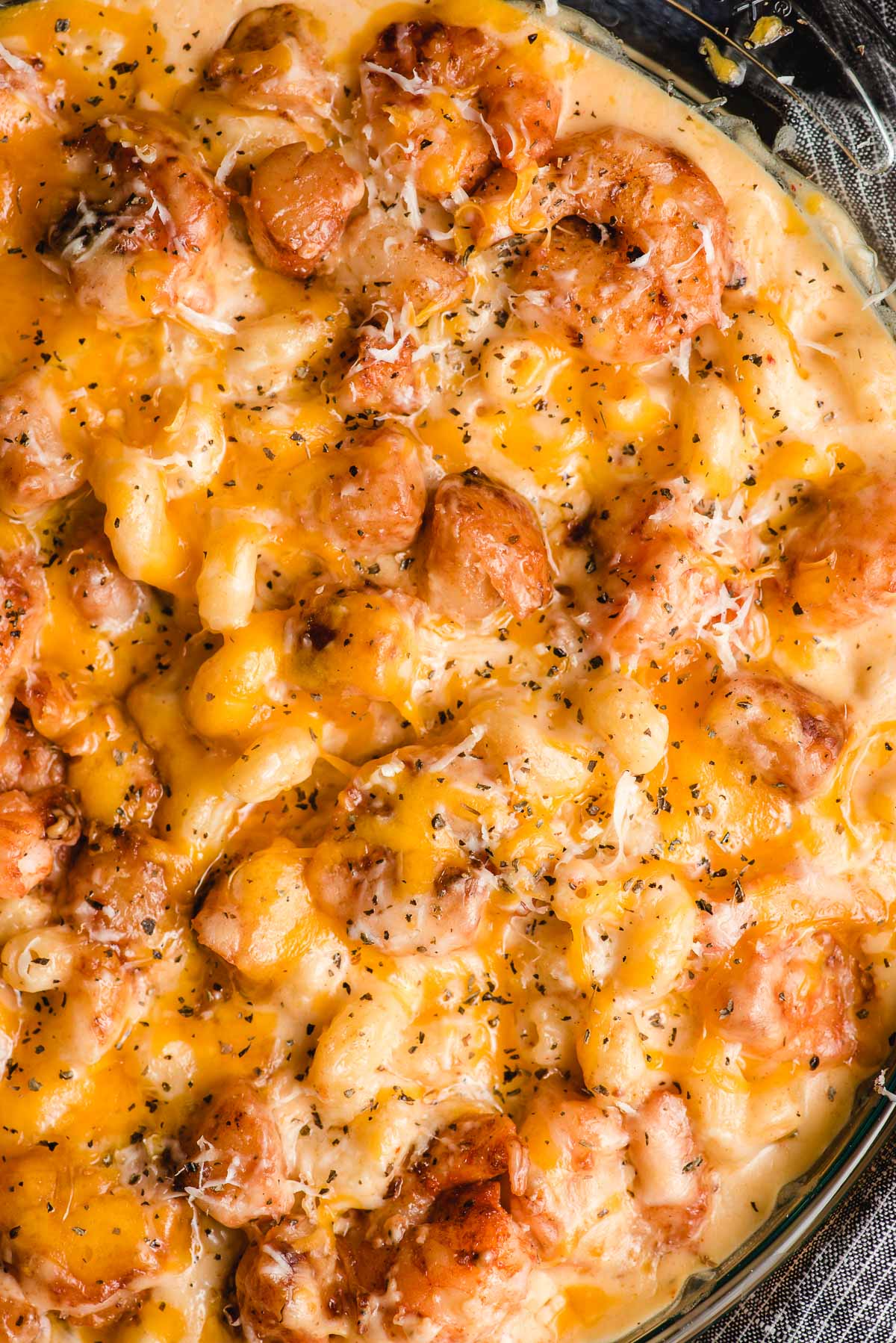 Up close image of freshly baked seafood mac and cheese with melty browned cheese on top.