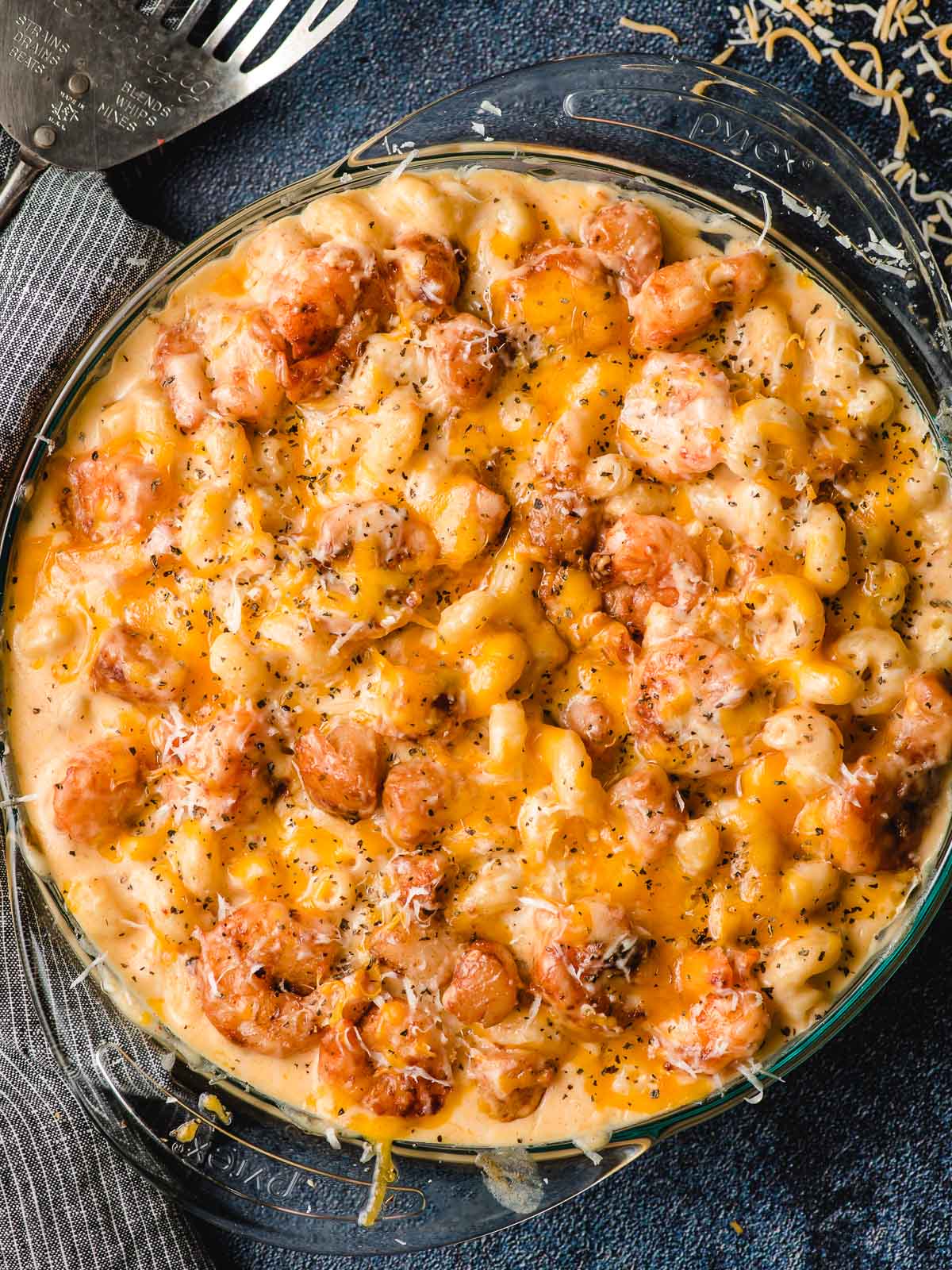 Baked Shrimp Mac and Cheese in a glass casserole dish on top of a dark colored table.