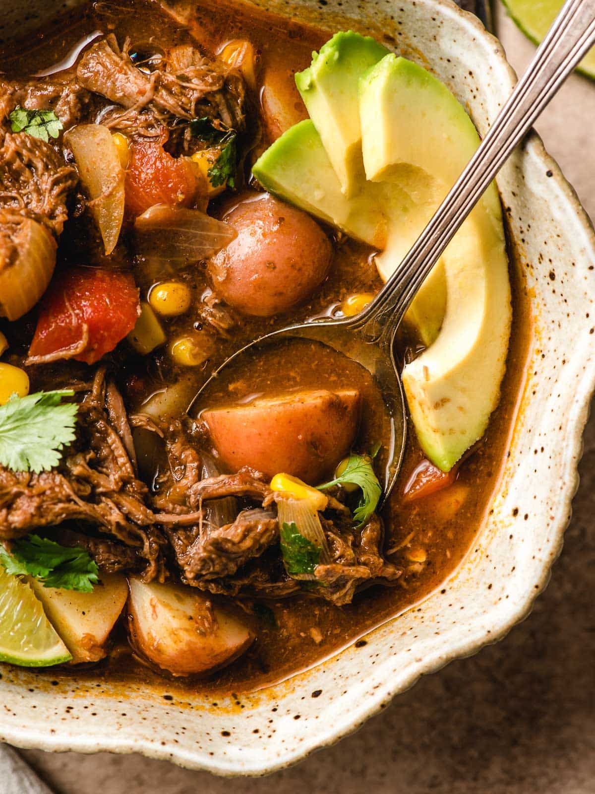 Spoon taking a bite out of a bowl of Mexican Beef Stew.