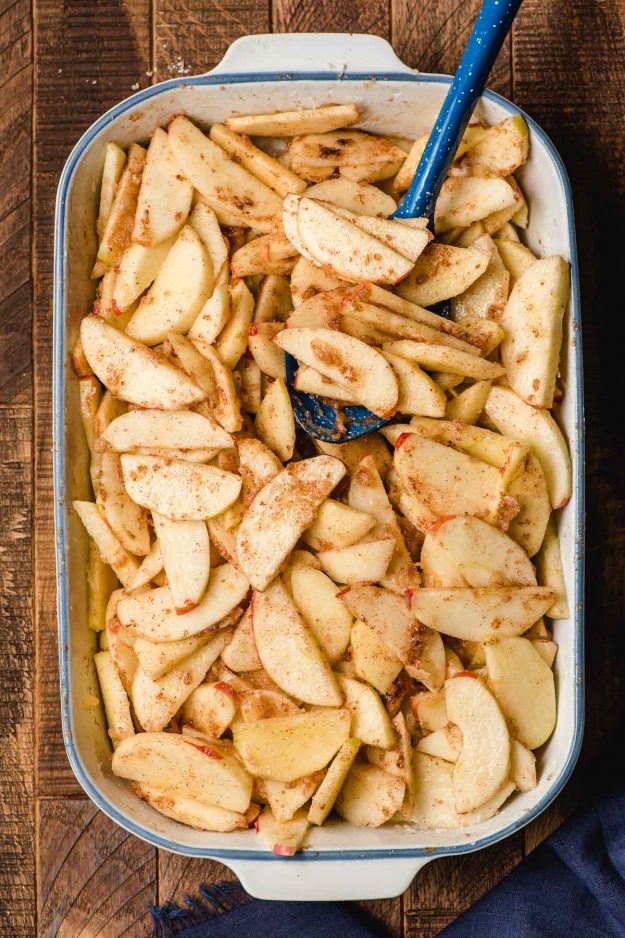 Uncooked cinnamon apple slices in a white casserole dish.