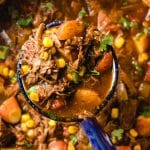 Scoop of Mexican Beef Stew in a blue and white ladle.