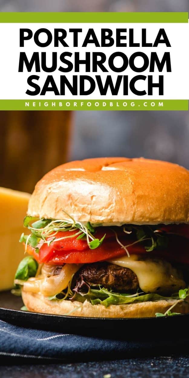 Portablleo mushroom sandwich with cheese, roasted red peppers, and sprouts on a dark plate.