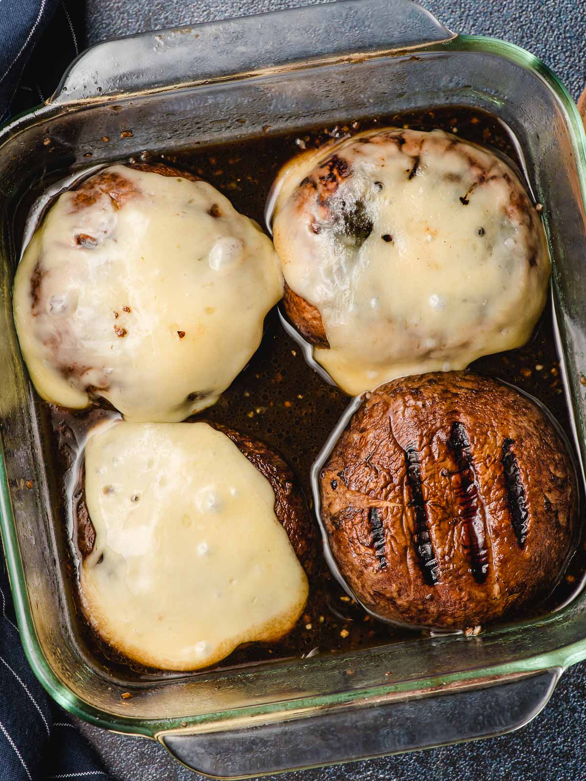 Four grilled portobello mushrooms with melted cheese on top.