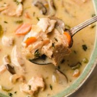 Spoonful of Creamy Turkey Soup with carrots and thyme leaves.