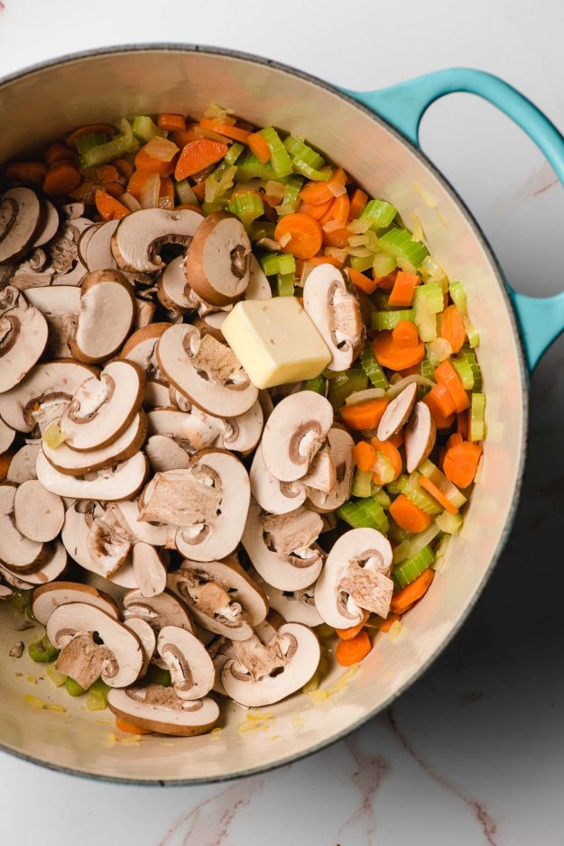 Dutch oven filled with mirepoix and mushrooms.