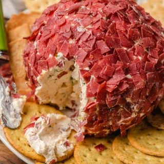 A chipped beef cheeseball served on a plate with crackers.